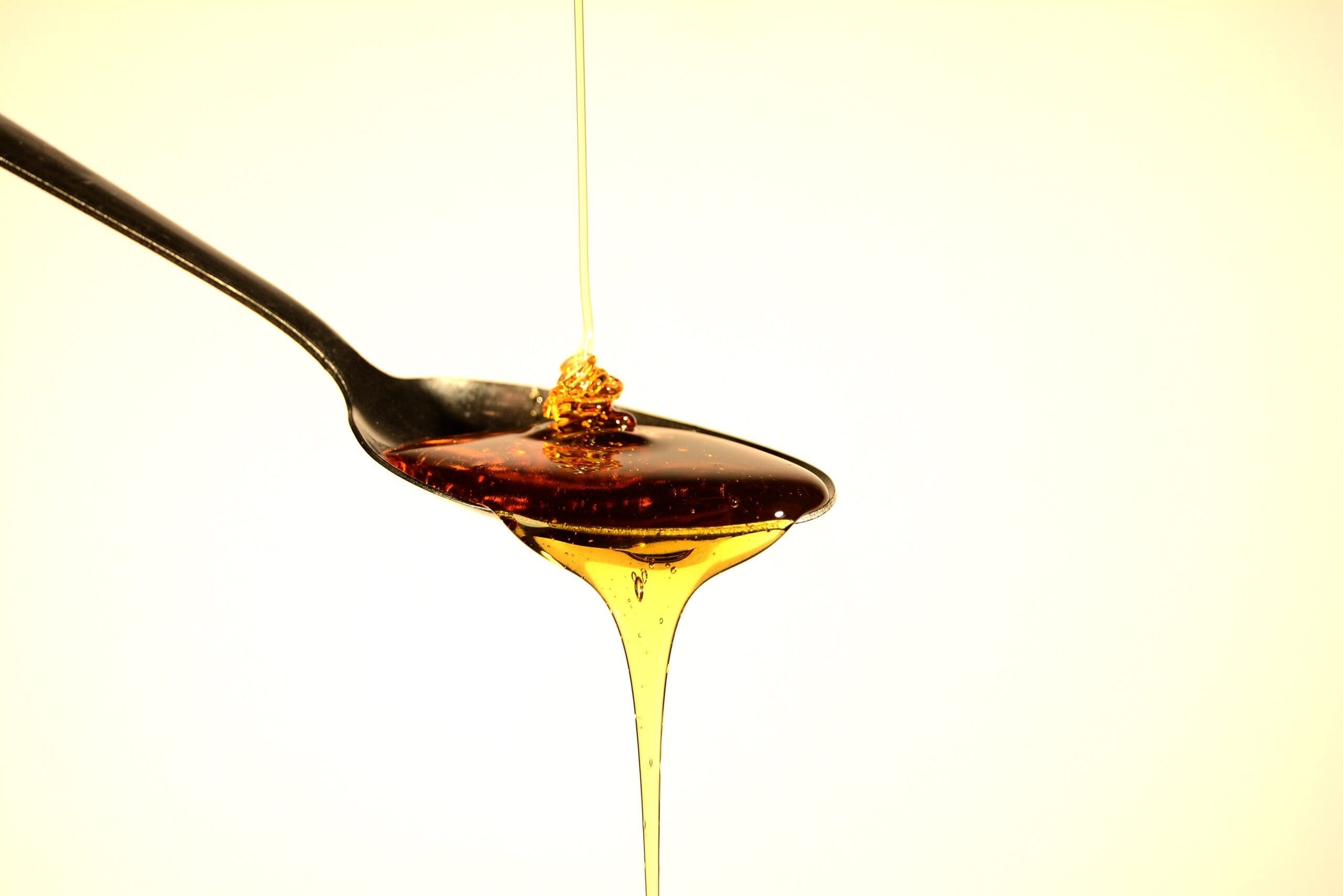 an overflowing spoon with honey drizzling in